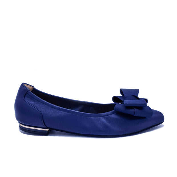 Single royal blue flat shoe with a bow detail and gold heel trim, shown in profile on a white background