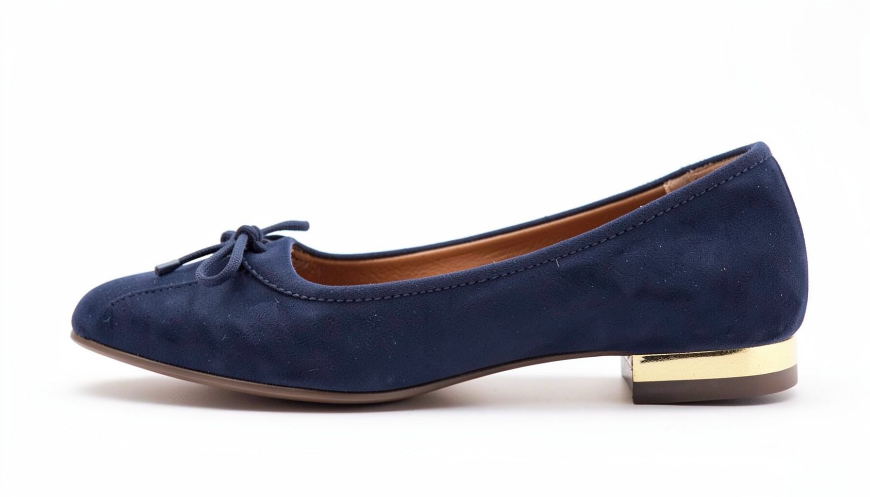 Close-up of dark navy flat shoe with bow detail and gold heel trim, shown in profile on white background