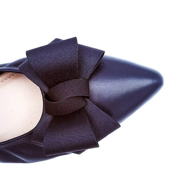 Close-up top view of a black pointed-toe flat with a grosgrain bow on a white background
